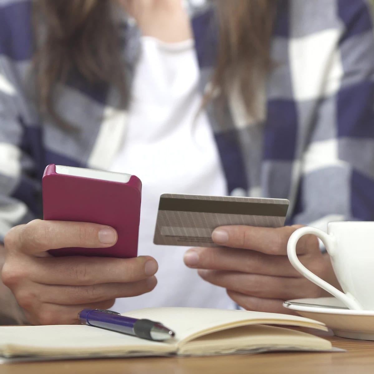 Young female smartphone credit card shopping A young female buying goods with a smartphone and credit card in her hands