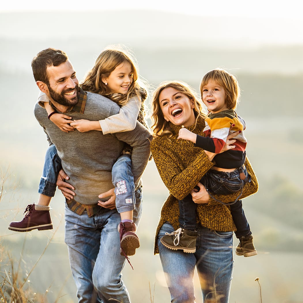 Family autumn walk A young happy family with parents and two kids enjoying an autumn walk on a hill