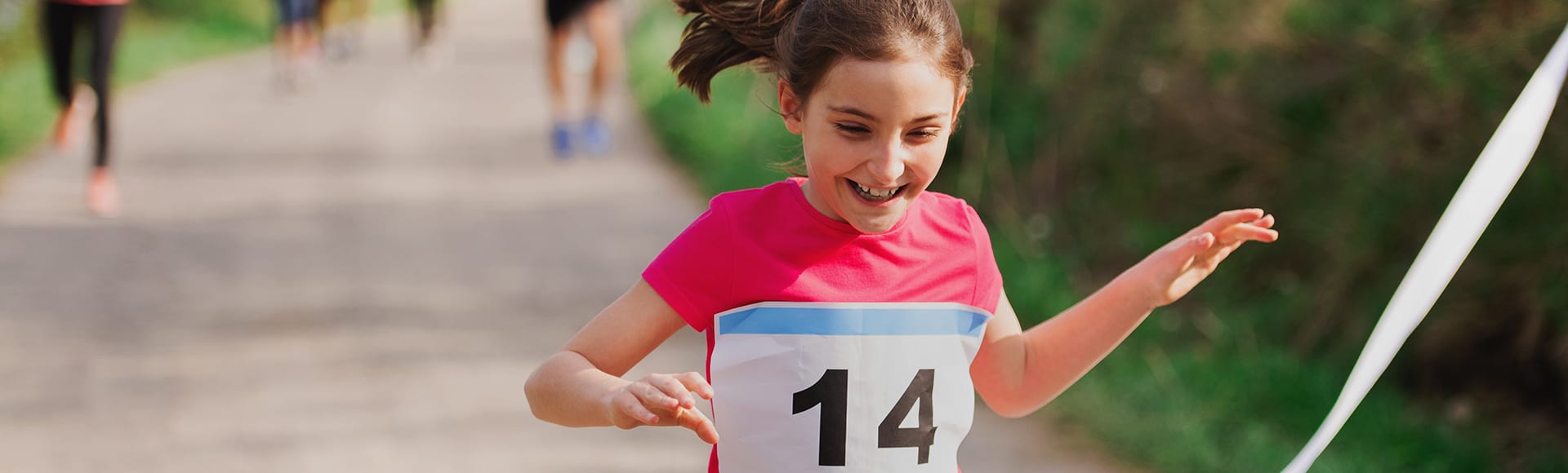 A small girl runner crossing finish line in a race competition in nature.