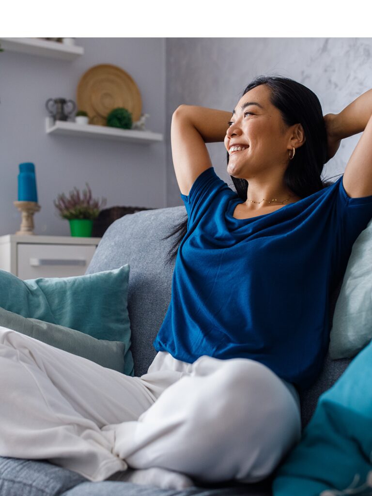 Image of a woman sitting on her couch. She looks comfortable and happy.