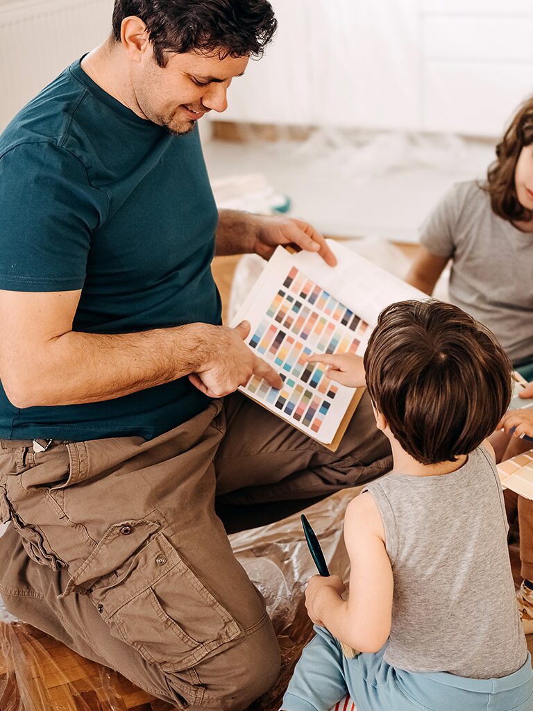 A man looks at picture books with his two young children