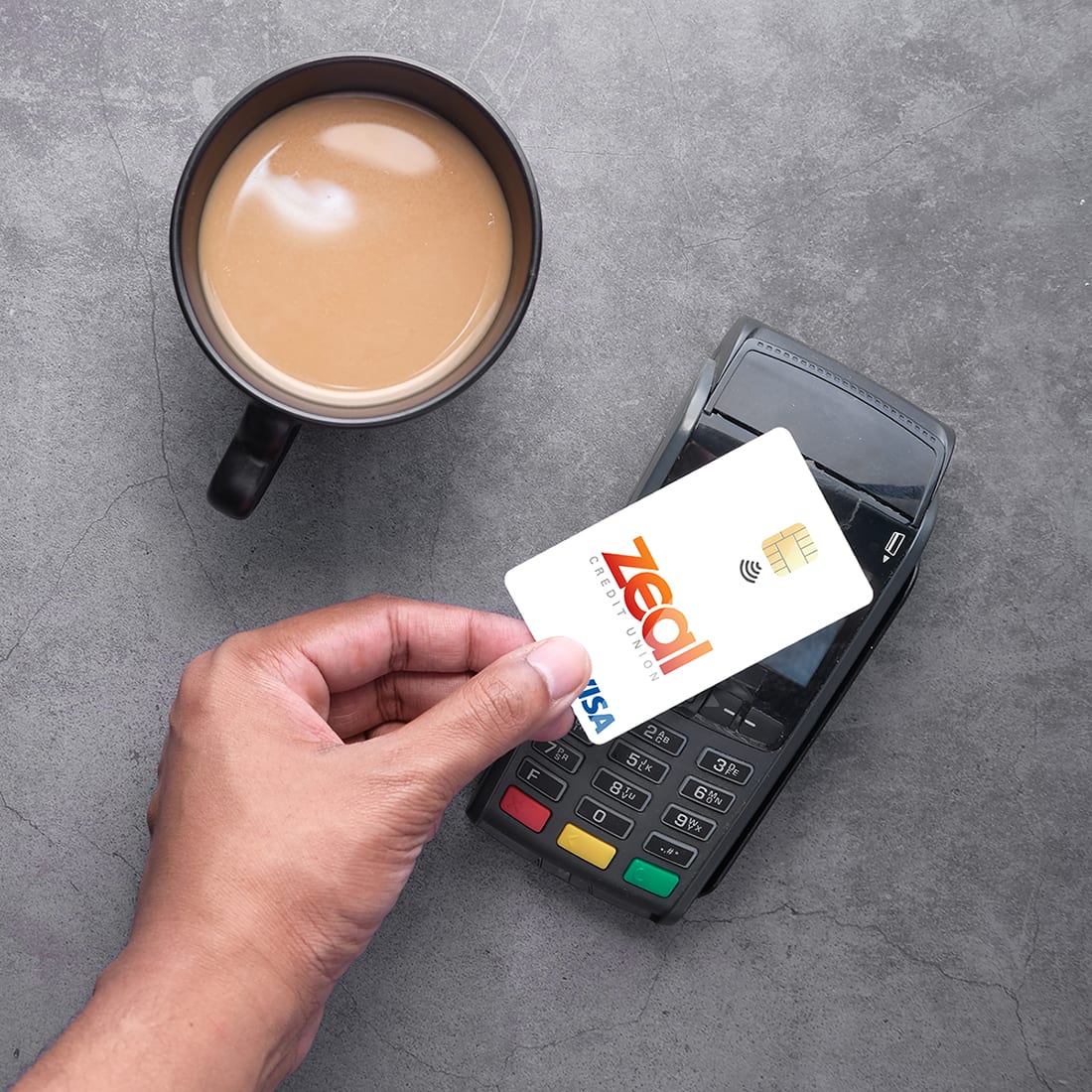 Payment terminal charging from a card, contactless payment Zeal Tap to Pay. Hand holding Zeal credit card over wireless payment system.