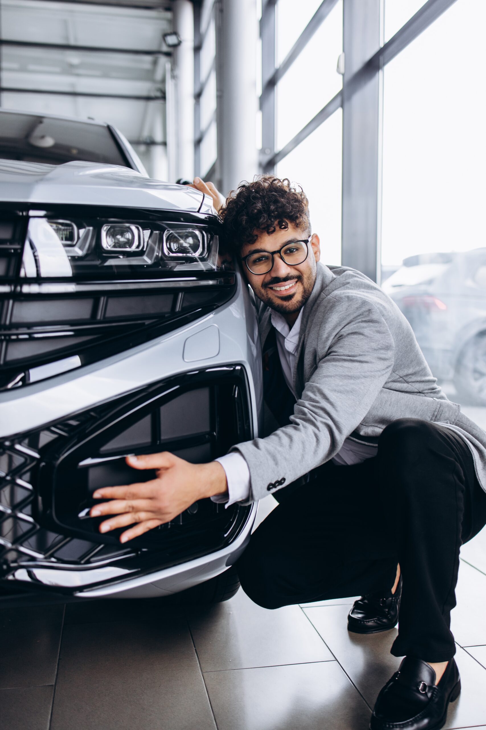 Man smiling and hugging the front of his new SUV.